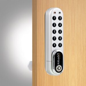 A silver kl1000 g3 electronic locker lock with circular black numbers fitted to a wooden locker door.